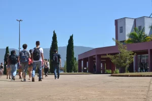 A imagem mostra alguns estudantes caminhando de costas no campus Morro do Cruzeiro, da UFOP